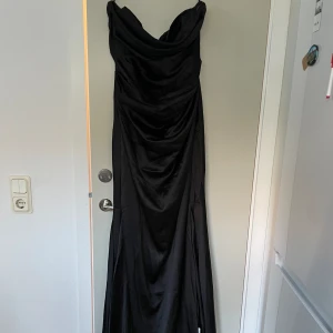 Dubbletter av svart långklänning  - Svart silkesklänning, bandeau. Nyskick och helt oanvänd från Asos. Nypris 1569kr och slutsåld på hemsidan  Köpt dubbletter av samma klänning i samma storlek, finns ytterligare annons för den.  
