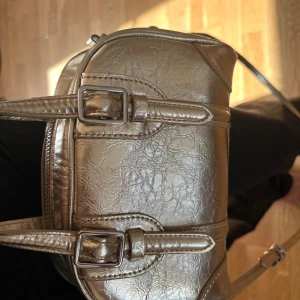 Guldig väska ifrån Zara - Väskan är i bra skick men tyvärr saknas dragkedjan som ni ser på bilden men det går fortfarande att öppna samt stänga väskan utan problem.