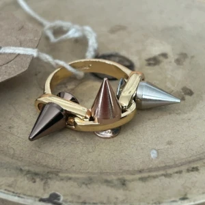 Ring - Unik guldfärgad ring från joomi lim med nitar i färgerna silver, brons och rosé. Skulle säga att den passar på långfingret eller tummen. Det är rostfritt stål.