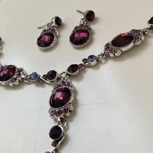 Smyckeset lila - Vackert smyckeset med örhängen och halsband i mörklila och violett  Okänt material 