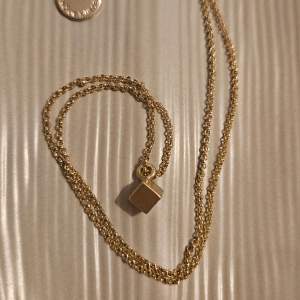 Ett fint, äkta guldhalsband från  SNÖ Of Sweden. Halsbandet har en tunn guldkedja med ett hänge i form av en liten kub.   Kedjan är ca 55 cm lång kuben ca 4 mm3   Bara använt det en gång så väldigt bra skick!