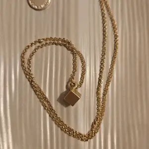 Ett fint, äkta guldhalsband från  SNÖ Of Sweden. Halsbandet har en tunn guldkedja med ett hänge i form av en liten kub.   Kedjan är ca 55 cm lång kuben ca 4 mm3   Bara använt det en gång så väldigt bra skick!