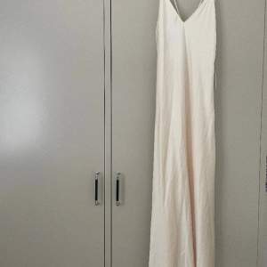 Långklänning från Zara, beige silkes klänning med med öppen rygg. Nyskick då den bara är testad och lappen är kvar. Strl XS