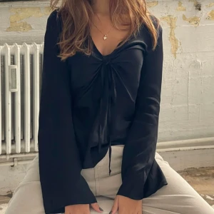 Satin blus  - Säljer denna svarta superfina satinblus med knytning från Design by si. Storlek XS/S. Säljer då den tyvärr är för liten för mig. Aldrig använd, endast provad. Köpt för 378 kr + frakt.