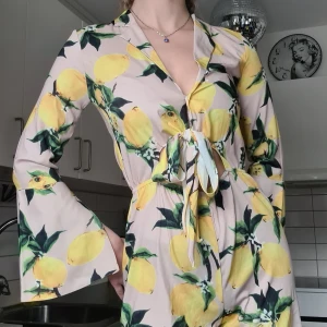 Playsuit Citroner Aeryné - Playsuit med citroner, V-ringad med knapp och knytning. Slits i ärmarna. Helt oanvänd med lappen kvar, nypris 500:-.  (Säljer en likadan i storlek M)  Material: 100% Polyester. 