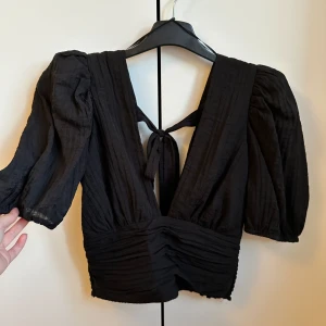 Fest topp/blus - Super snygg fest topp med lite djupare urringning, ballongärm och knytning i ryggen. Lite luftigare material.  Använd vid ett tillfälle, jättefint skick! 🖤  Nypris 399kr 