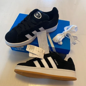 Nya Adidas Campus 00 - Adidas originals Campus 00s j Storlek: 37 1/3 Färg:CBLACK/FTWWHT/FTWWHT (svarta med vita ränder)  Ingår både svarta och vita skosnören.   Nya och oanvända. Ligger kvar i kartong. 