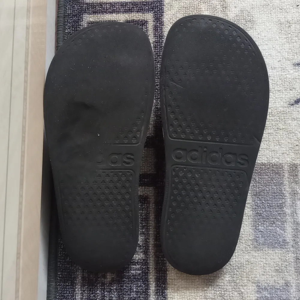 Säljer mina Adidas tofflor. De är lite slitna som man kan se och på baksidan av skorna finns det en inbuckla typ, se bild 3. Men det påverkar inte bekvämligheten alls. Det står ingen storlek på, men skulle gissa på 38 1/2. Köparen står för frakten! . Skor.