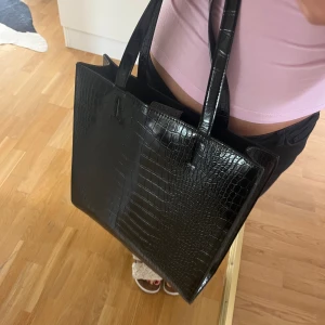 Väska  - Rymlig svart väska med mönster. Väskan är köpt på Lindex och är i nyskick. Nypris 499kr. Säljer då jag inte använder!! Mitt pris: 350kr. Hör av dig vid frågor<3