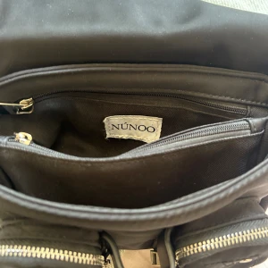 NÚNOO väska  - En jättefin (och äkta) Núnoo väska! Väskan är köpt på Plick och baga används fåtal gånger av mig och den tidigare ägaren= nyskick, utan defekter! Väskan är en mindre handväska men med många fack som gör att mycket får plats!!! ❤️