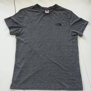 North Face tshirt grå - En grå t-shirt från The North Face i storlek M. T-shirten har korta ärmar och en rund halsringning och är tillverkad i ett mjukt och bekvämt material.