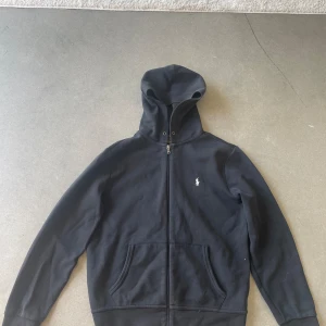 Ralph lauren double knit full zip hoddie - Hej! Jag säljer nu min Ralph lauren full zip hoodie då den är för liten för mig. Den är i bra skick men snörena från luvan är borta men påverkar inte hoodien dåligt. Skriv till mig för frågor om den.