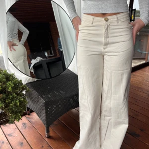 Krämvita kostymbyxor - Krämvita kostymbyxor, mid-waist med vid passform.  Fraktkostnad tillkommer. 