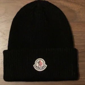 Moncler Mössa -  Moncler mössa  Helt ny! Passande till det kalla vädret och väldigt stilren.  