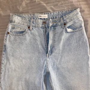 Zara Straight Fit Jeans I Ljusblå, Storlek 40 (US 8-10) - Zara Straight Fit medel/hög midja Jeans i färgen Ljusblå. Rivna jeans vid knäskål. Normal fit med kedja. Storlek 40, passar till folk med storlek M i byxor. Jag är 163cm lång. Använd några gånger. 