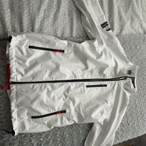 Helly Hansen Jacka  - En vit Helly Hansen jacka nästan helt oanvänd. Passar bra som vår/höst jacka. Passar till både tjej och kille. Ny pris 1600.