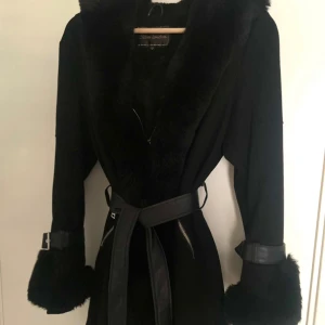 Chica London Vinterjacka i fuskpäls  - Figursydd svart fuskpäls jacka   tillhörande skärp - avtagbart, finns slitage på skärpet  Päls - avtagbar (går att byta ut om man vill eller tas av tillfälligt vid tvätt)  Storlek - 10 motsvarande M Ord.pris - 1500kr 
