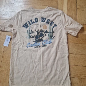 Western t-shirt storlek XS - Köpt på walmart I USA, alla lappar kvar. I barnstorlek, men sitter som en croptop på mig som är 160 cm lång.