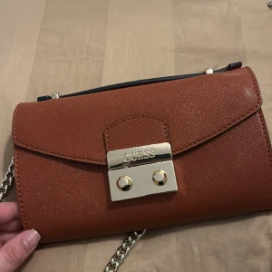 Guess väska  - En helt oanvänd Guess väska med fina detaljer köpt för ungefär 1000kr och säljs för 500kr då den ej är använd. Pris kan diskuteras vid snabb affär. 