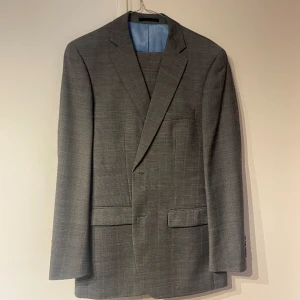 Helt nytt grått kostymset från dressman  - Ett helt nytt väldigt fint kostymset som aldrig har varit använt, från Dressman. Det är i grårutigt mönster. Byxorna är i storlek 30-32 och kavajen i storlek 50 (M)