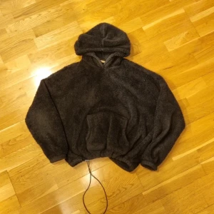 Lurvig Svart Hoodie - Lurvig Svart Hoodie. Väldigt bra skick. Längd 60 cm, Bredd 66cm, Arm 43 cm. Man kan spänna åt hoodie så den sitter bättre