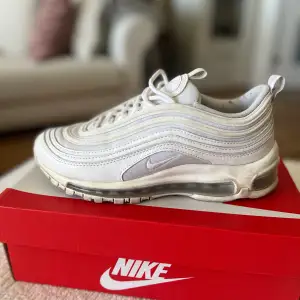 Vita Nike 97’s som har reflex på skorna.