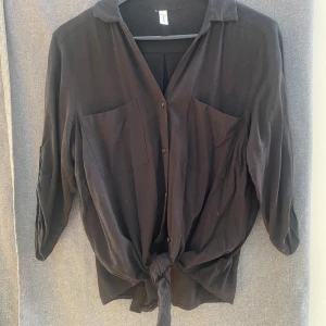 Knytblus - Svart knytblus mer knappar. 