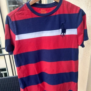 Polo Ralph Lauren Striped Tee, boys size 14-16 years - Snygg randig tisch från Polo Ralph Lauren, köpt på Macy’s i New York och i väldigt gott skick. Killstorlek 14-16 år men stor så funkar även som herrstorlek Small. Kan mötas i Sthlm!