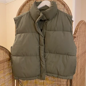 Cropped väst  - Snygg croppad puffer väst från weekday i fin olivgrön färg. Dragskor i botten för mer bomber passform, mycket bra skick! Nypris 600kr.