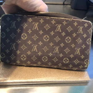 Vintage Louis Vuitton plånbok  - Jättefin, äldre vintagemodell med många praktiska fack för kort, sedlar och givetvis ett fylligt myntfack.  Som synes på ena bilden är tyget något skavt längst med dragkedjan men förutom det är denna gamla goding helt felfri!   Givetvis är den äkta