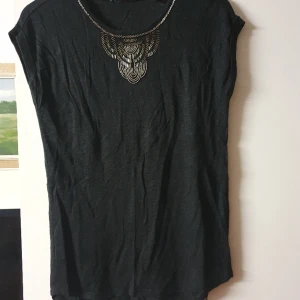 Dam T-shirt oanvänd  - Svart dam T-shirt med silvriga paljettdetalj fram. Stl M 