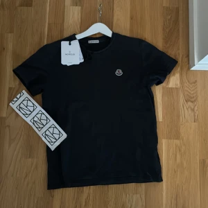Mobiler t-shirt  - Säljer min moncler t-shirt som jag köpte på nk. Jag säljer den för att jag har växt ut den. Priset går att diskutera. Skick 7/10