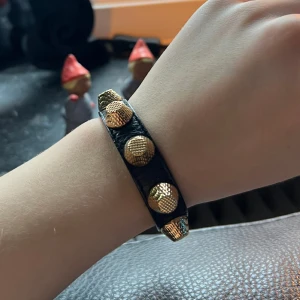 Balenciaga armband  - Ett svart balenciaga armband med gulddeyaljer. Strl M. Väldigt bra skick, fick detta av min syster och har bara använt det en gång.