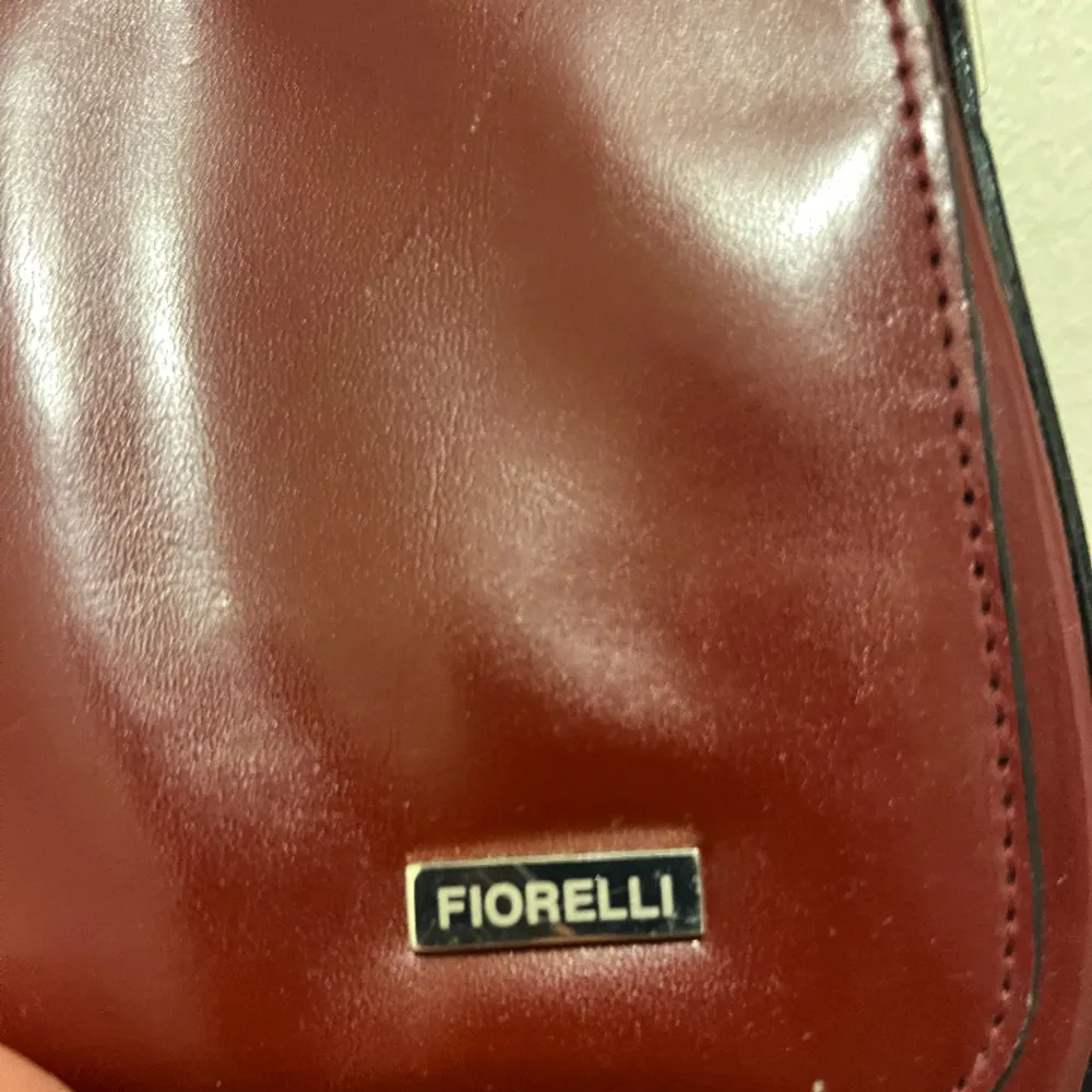 Väska från fiorelli i snygg röd färg köpt second hand. Defekter syns på bild 3. Väskor.