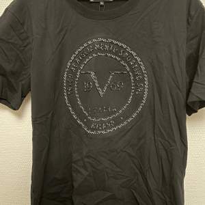 Säljer en svart Italia by Versace T-shirt med tryck i nyskick (lappen sitter kvar). Nypris 700kr. Storlek: XL (men är som en L).
