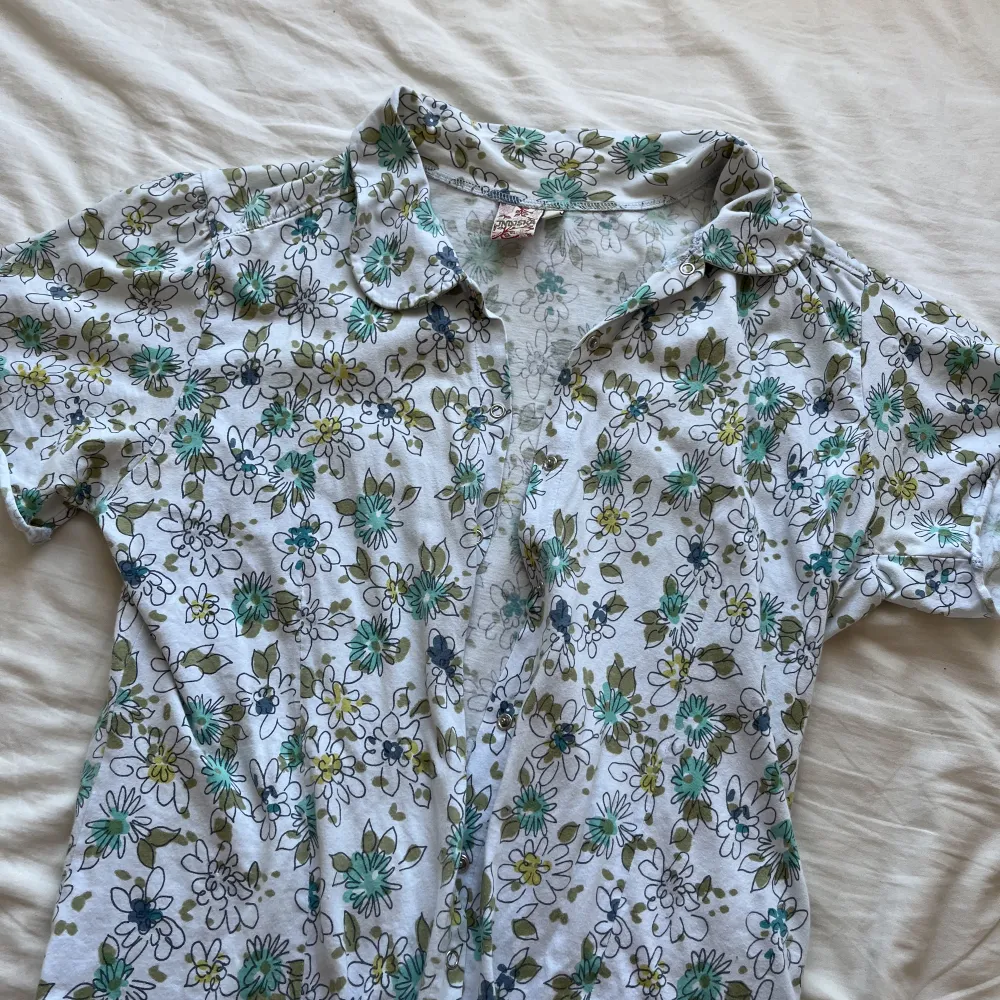 en söt blommig tröja med knappar som knäpps fram till. Det står att det är storlek xl men jag skulle säga att det är m. T-shirts.