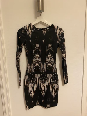 Klänning  - Fin klänning i mycket fint motiv. Klänningen är öppen i ryggen och är figursydd. Storlek xs