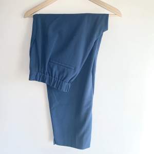 Ett par raka, 3/4 långa, blå kostymbyxor från Banana Republic. Byxorna är i bra skick och säljes då de inte kommit till användning. 
