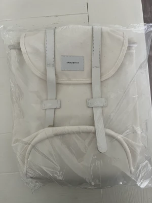Sandqvist ryggsäck  - Ny ryggsäck med lapparna kvar. Stig small unisex vit ryggsäck av Sandqvist, med övre handtag och central klaffstängning med dragsko.  Minimal design som gör det till en idealisk ryggsäck för alla tillfällen.  Nypris 1095kr
