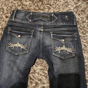 Utsvängda lågmidjade jeans med coola detaljer och knappar på fickorna.  Midjemått tvärs över: 36cm Innerbenslängd: 72cm 