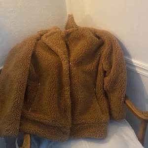 Teddy jacka - Brun teddy jacka i storlek M. Från Weekday. Med dragkedjor och nappar vid magen. Den går ner till Höfterna/ rumpan beroende på hur lång man är. 