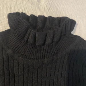 Polo tröja  - Svart polo tröja med fina volang  detaljer runt halsen och handleden, den sitter tajt och fin, stretchig material 