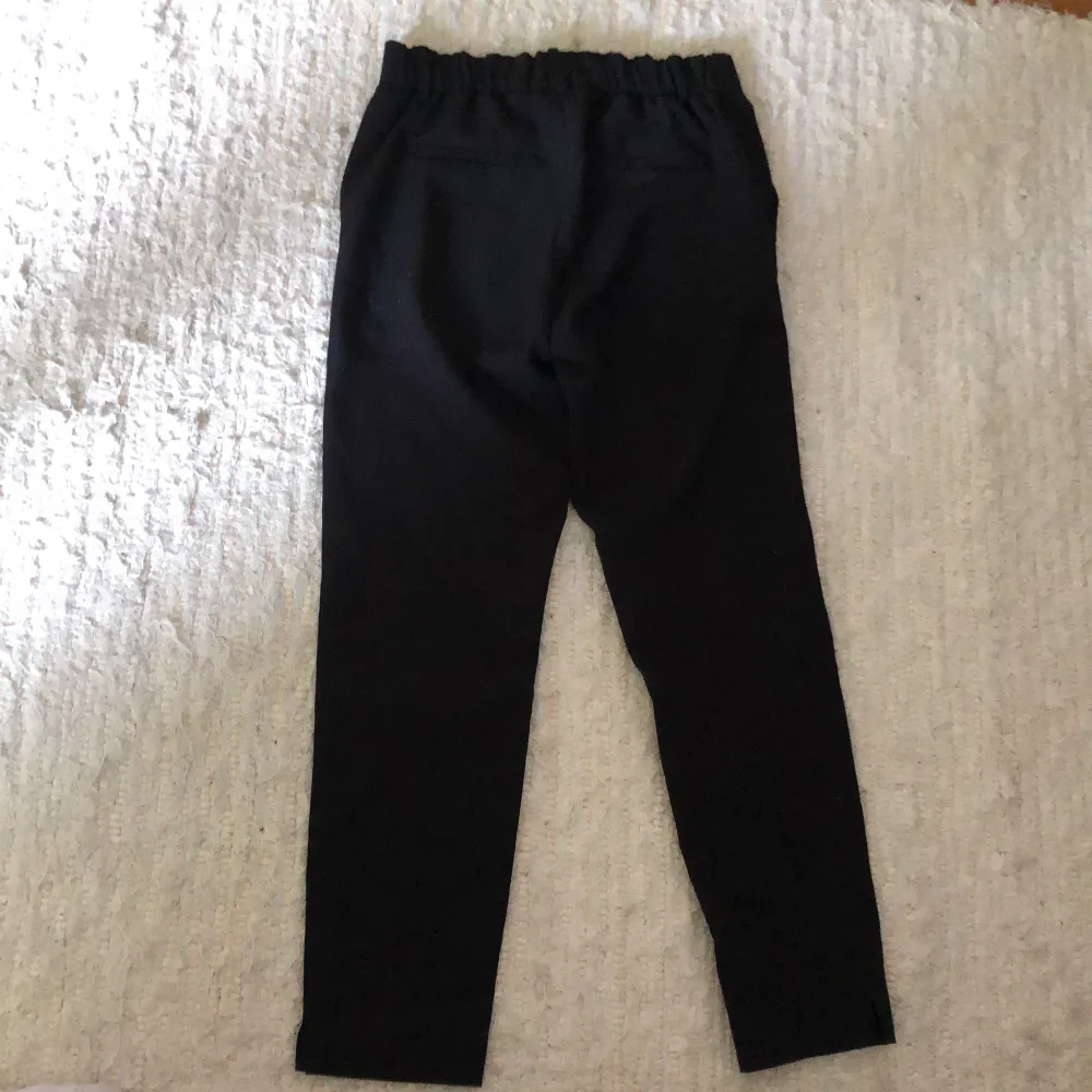 Svarta tygbyxor, som ser ut som kostymbyxor med resår i midjan . Jeans & Byxor.