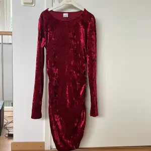 En mörkröd klänning med Scrunch på sidan som formar kroppen på ett smickrande sätt. Den är använd max två gånger (jul). 