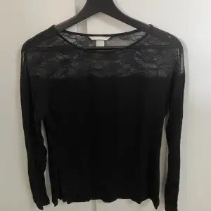 En svart långärmad tröja med spestdetalj. 
