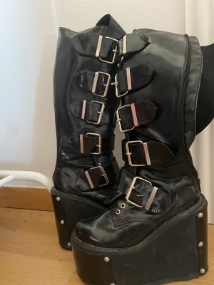 90-tals Demonia boots - Äkta demonia boots från 90 talet. Lite dammiga då de bara stått i flera år, men jättebra kvalitet. Kommer också med flera olika detaljer man kan byta på plattformsdelen , som nitar och eldsflammor. Storlek står inte men passar mig som har 37/38!