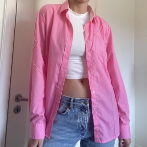 Barbierosa skjorta - Rosa skjorta med fina söm-detaljer längs ena bröstet och ärmen i storlek M.  