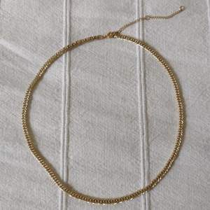 Skitsnyggt guldfärgat halsband. Kedja i metall med förlängning. Den guldiga färgen skiftar lite grann. Ca 47 + 7.5 cm långt. 
