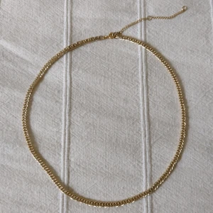 Halsband - guldfärgad kedja i metall - halskedja - Skitsnyggt guldfärgat halsband. Kedja i metall med förlängning. Den guldiga färgen skiftar lite grann. Ca 47 + 7.5 cm långt. Kan skickas med ett frimärke (22 kr).