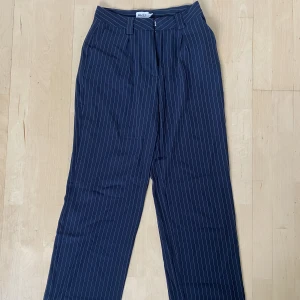 Randiga kostymbyxor - Randiga kostymbyxor från nakd med hög/medelhög midja. Byxorna är marinblåa med vit rand och i mycket bra skick!